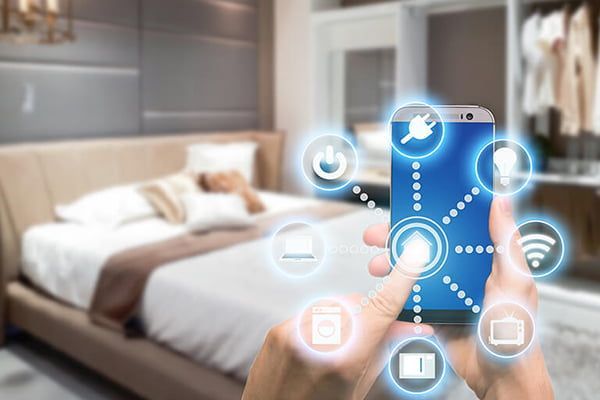 Person using phone to control smart home devices in a bedroom.