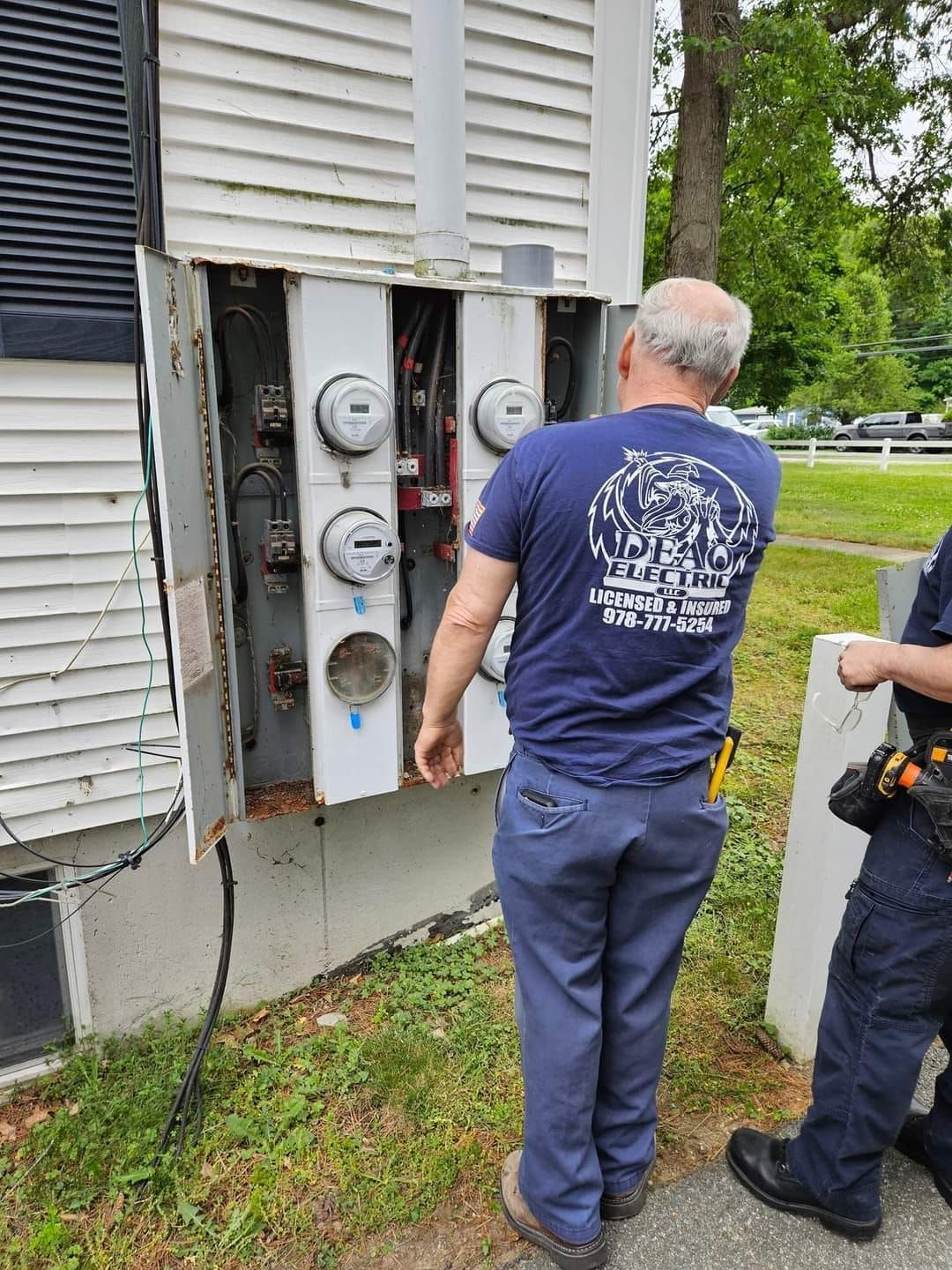 A man in a blue shirt is working on an electrical box.