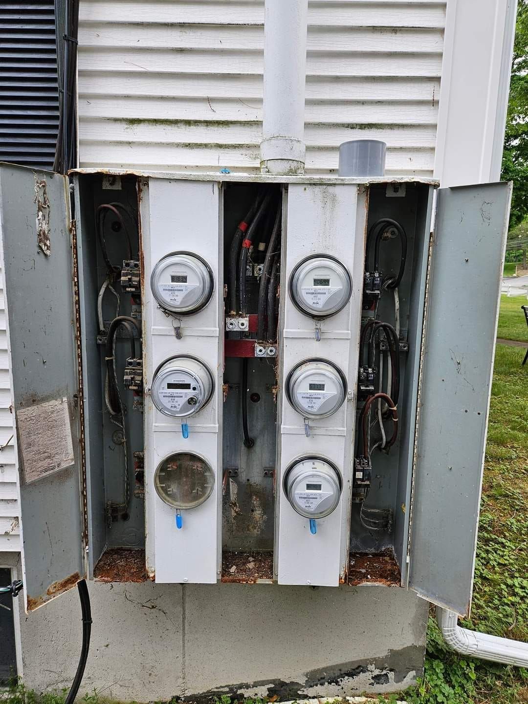 A white box with a bunch of electrical meters inside of it.
