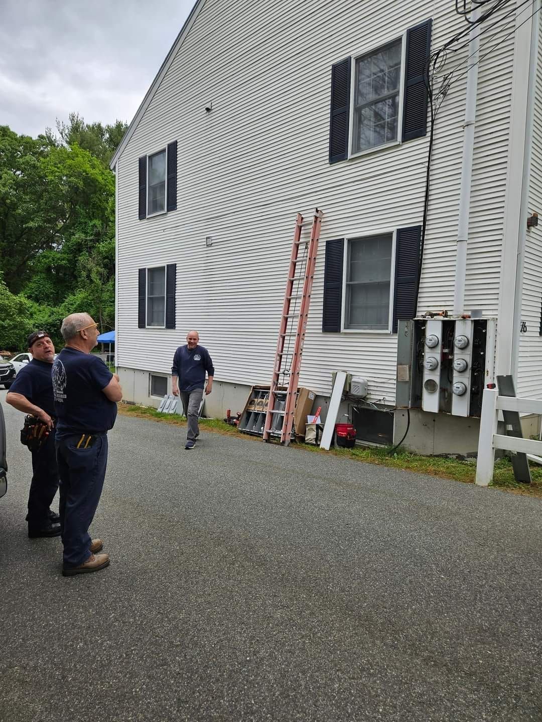 A group of men are standing in front of a white house.
