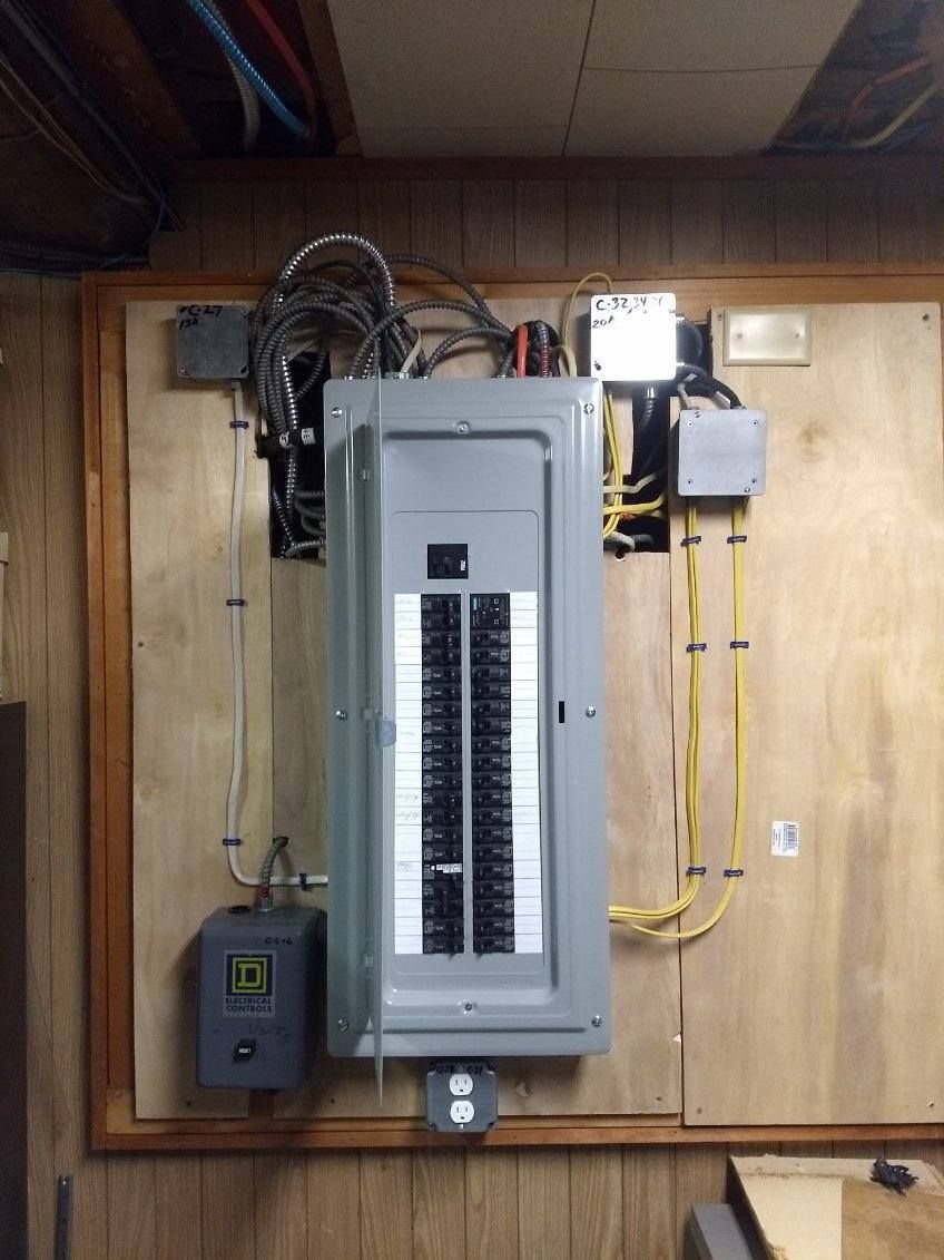 A large electrical box is hanging on a wooden wall.