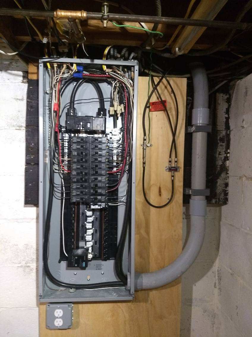 A electrical box is hanging on a wall in a basement.