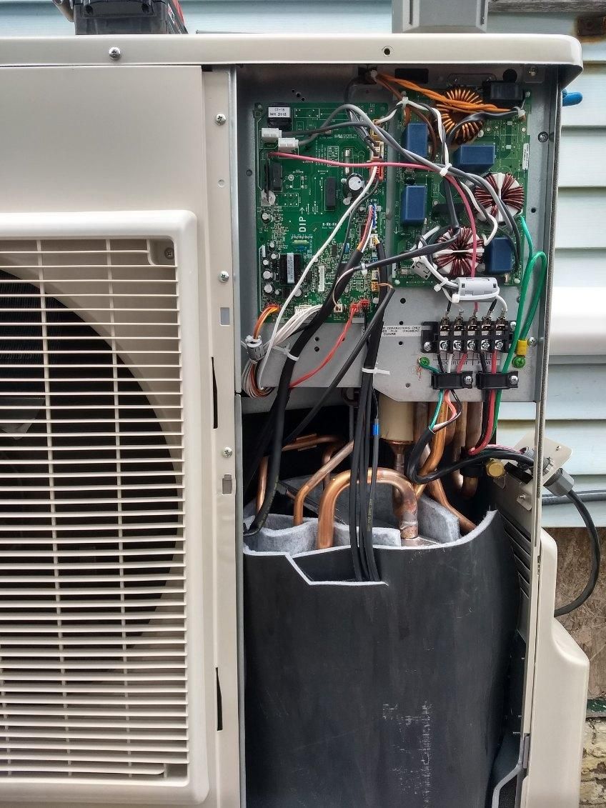 The inside of an air conditioner with a lot of wires coming out of it.