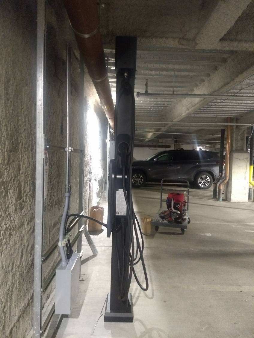 A car is parked in a parking garage next to a pole.
