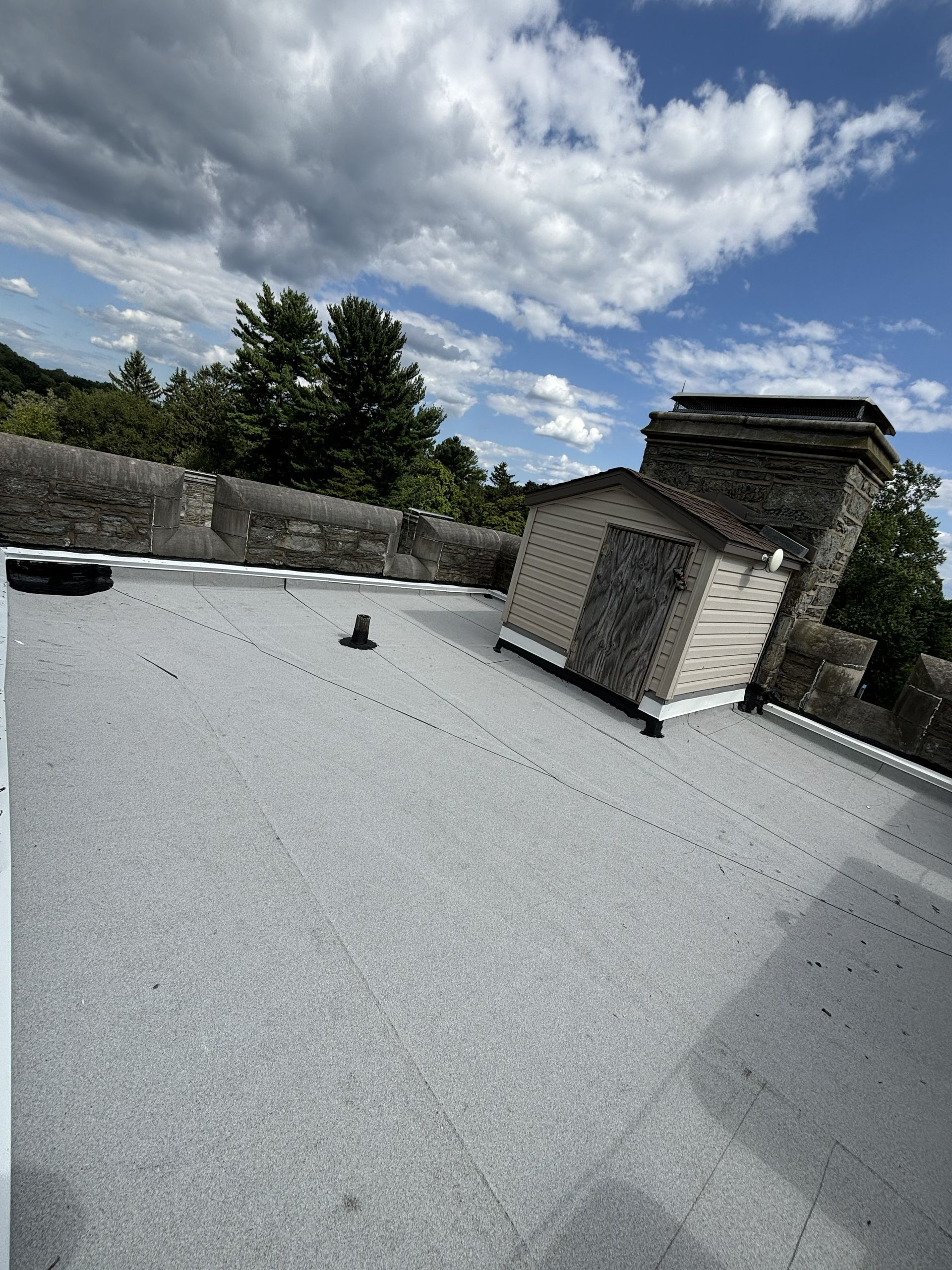 Rooftop with white gravel, a chimney, and cloudy sky overhead