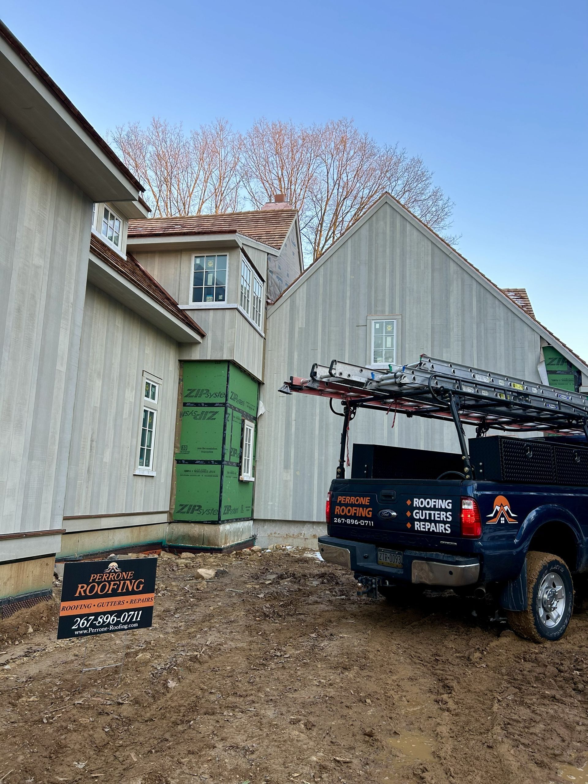 House exterior with green door, blue truck, and muddy driveway under a clear sky