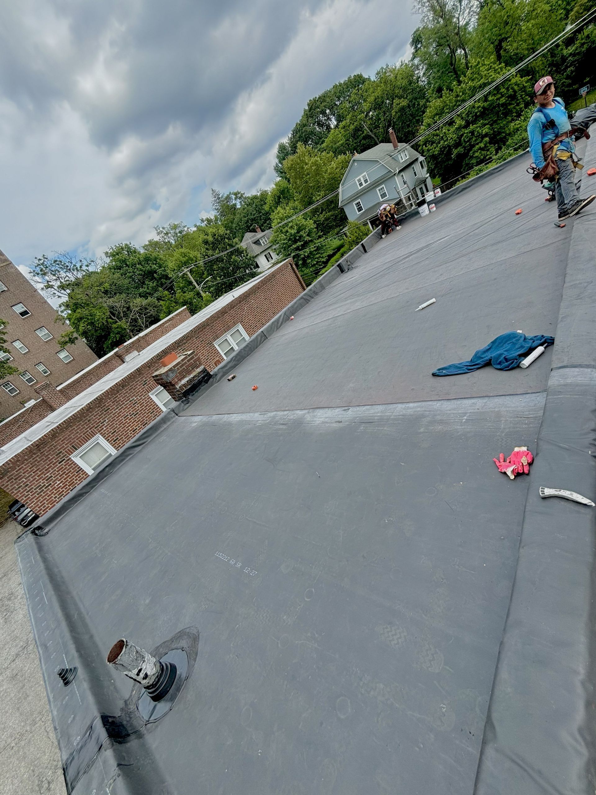 Rooftop with gravel surface, cloudy sky, and a person riding a bicycle near scattered items.