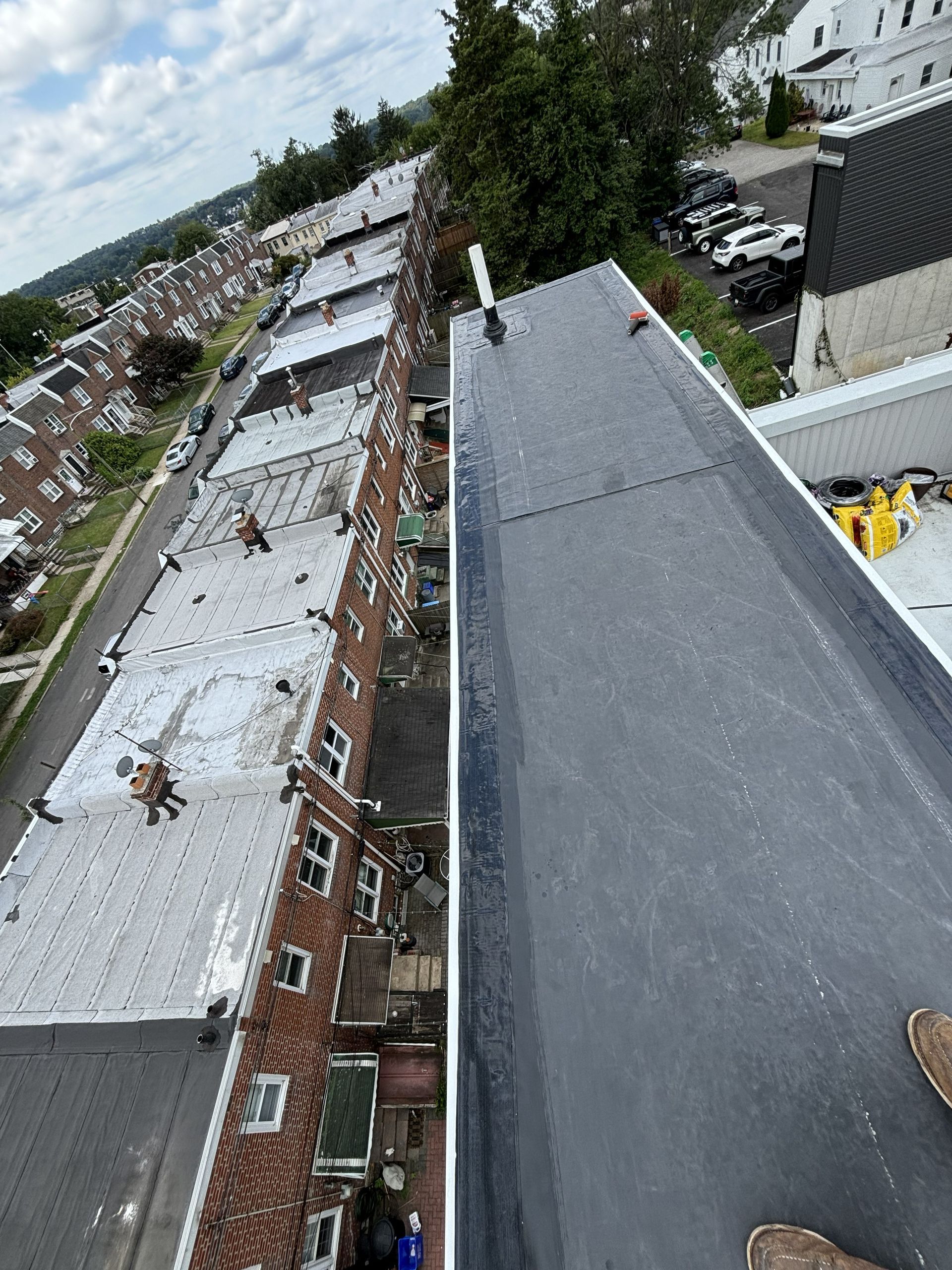 Rooftop view over row houses and a dark slate roof under a cloudy sky