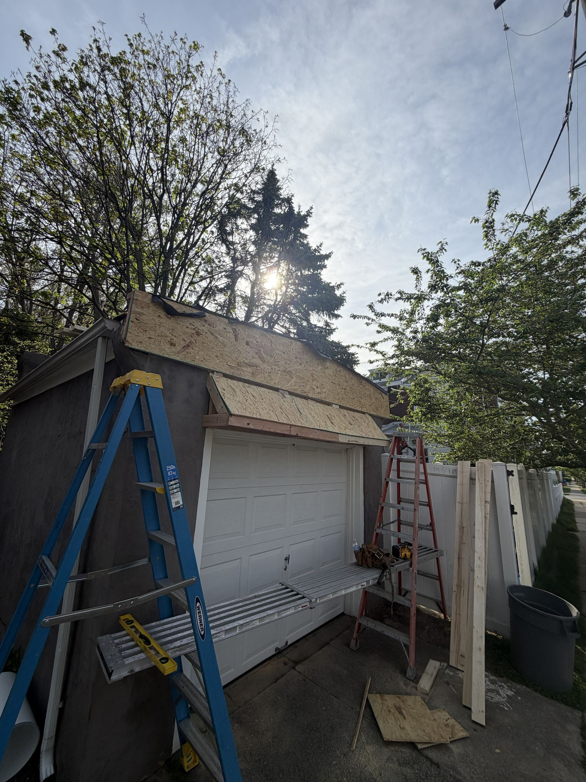 Workers’ scaffold and ladders beside a small shed under repair in a backyard