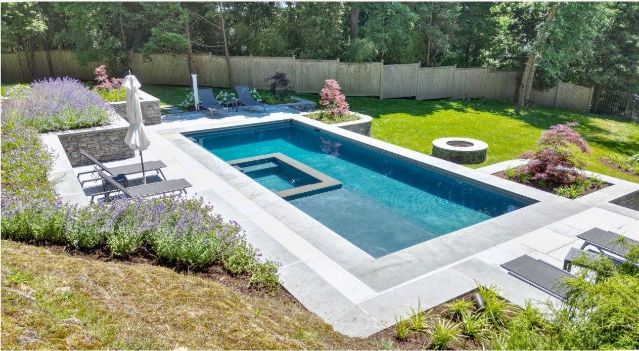 Grey stone pool with matching fire pit on green lawn