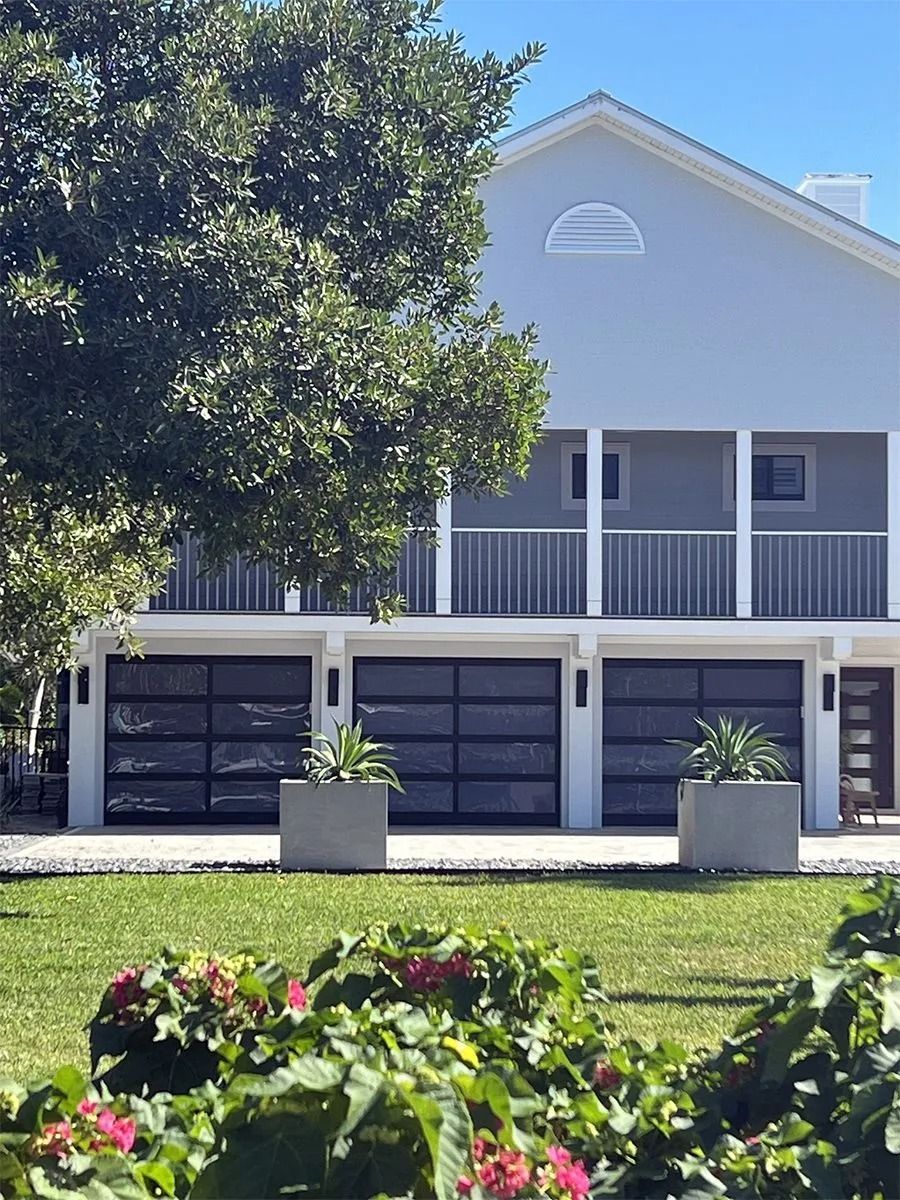 Modern house with three garage doors, balcony, and manicured lawn.