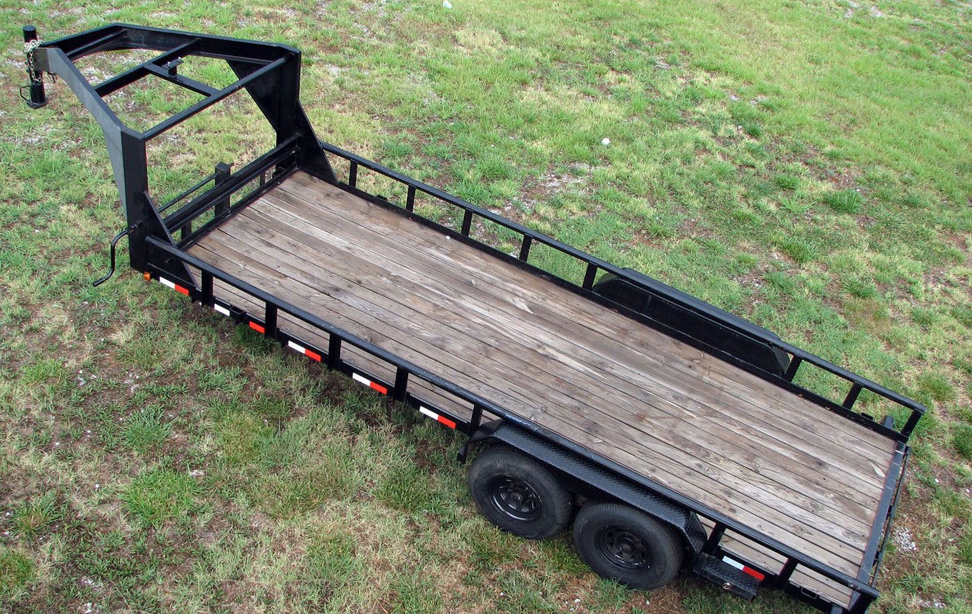 Black flatbed trailer on green grass.