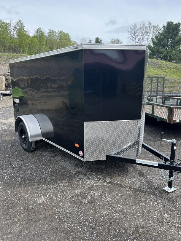 Black enclosed cargo trailer on a gravel surface.