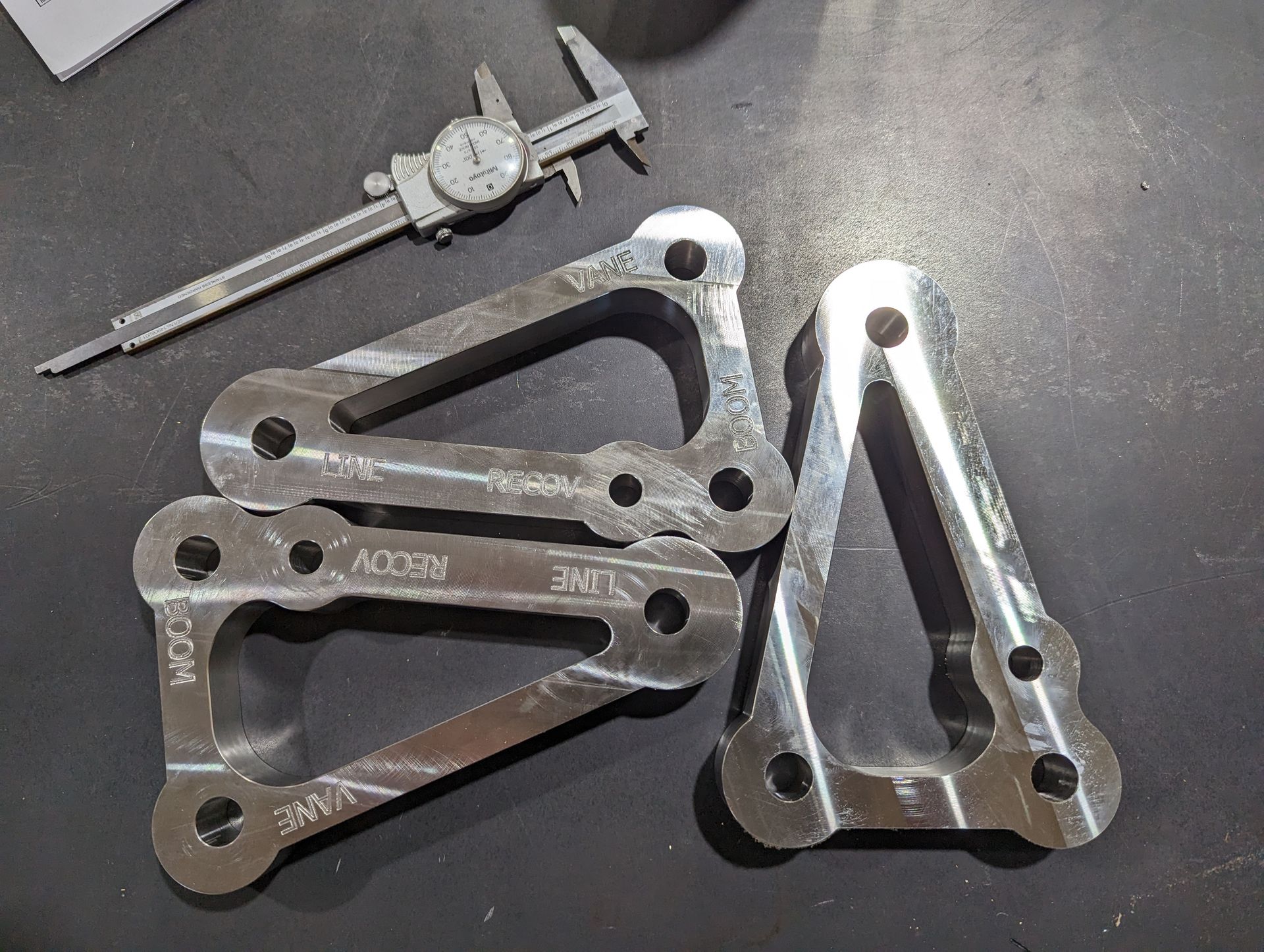 A pair of calipers sitting next to a piece of metal