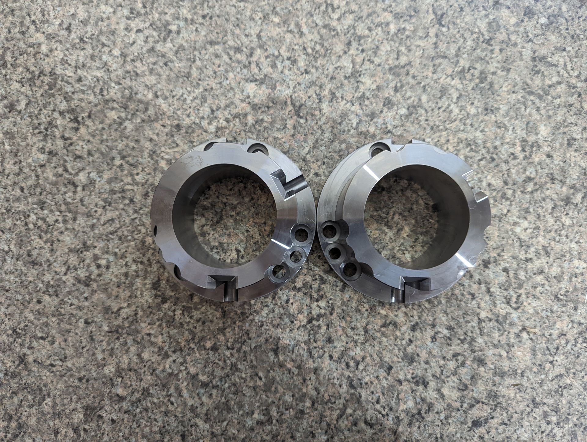 Two metal rings with holes in them are sitting on a marble surface.