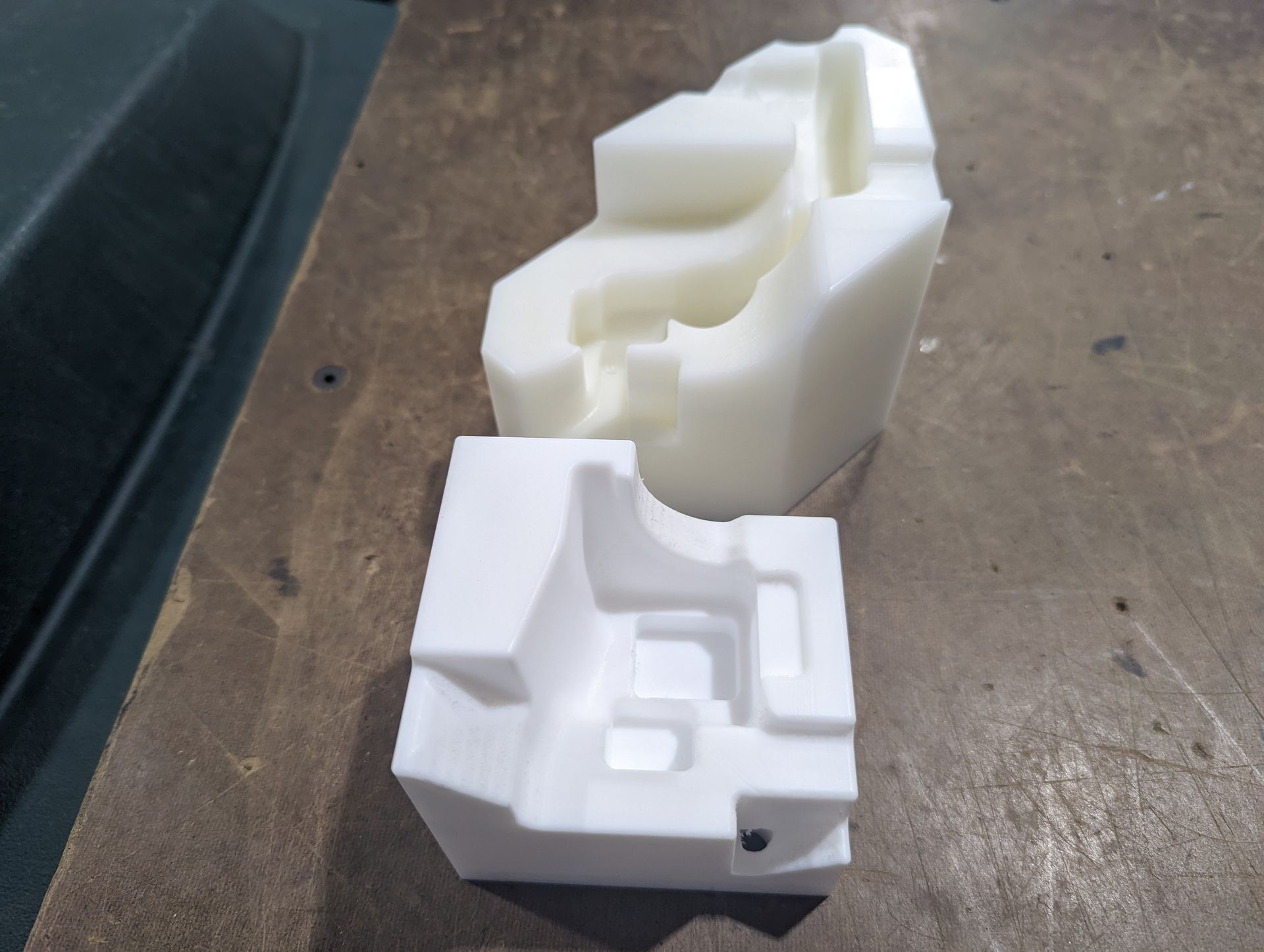 Two white plastic blocks are sitting on a wooden table.