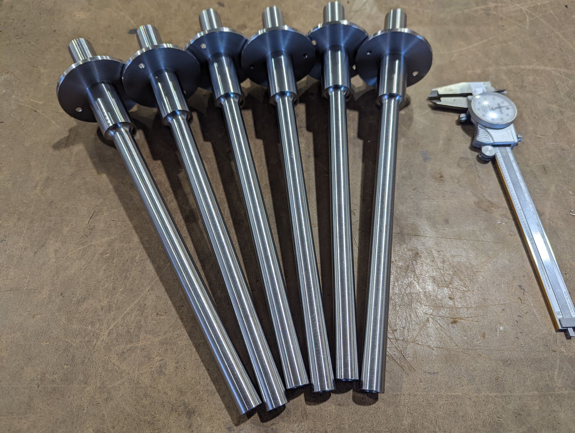 A pair of calipers next to a bunch of metal rods.