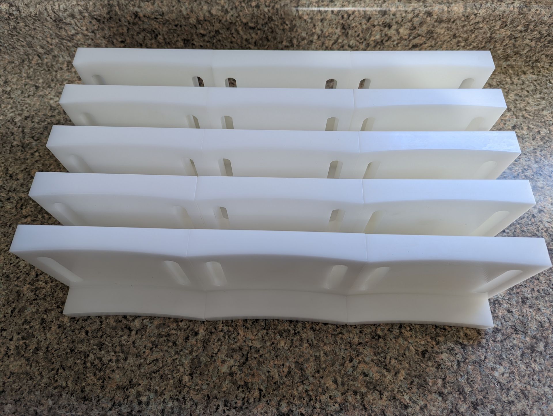 A row of white plastic trays are stacked on top of each other on a counter.
