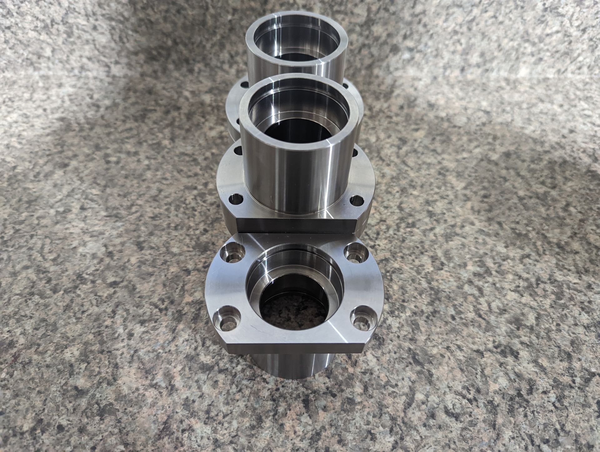 Three metal pieces are stacked on top of each other on a granite surface.