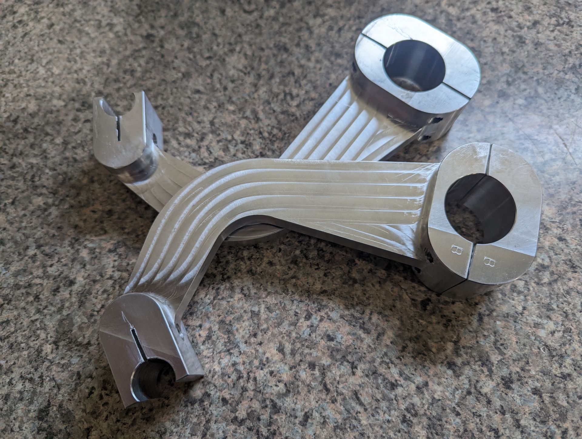 A pair of metal handlebar risers are sitting on top of a granite counter.
