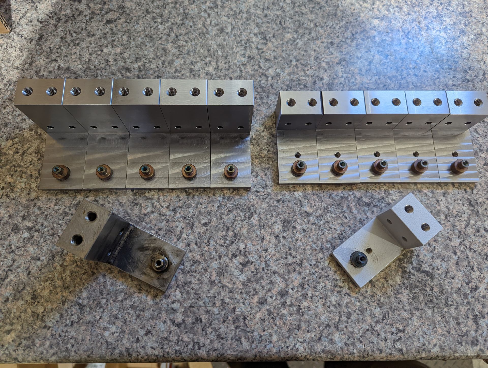 A bunch of metal pieces are sitting on a granite counter top.