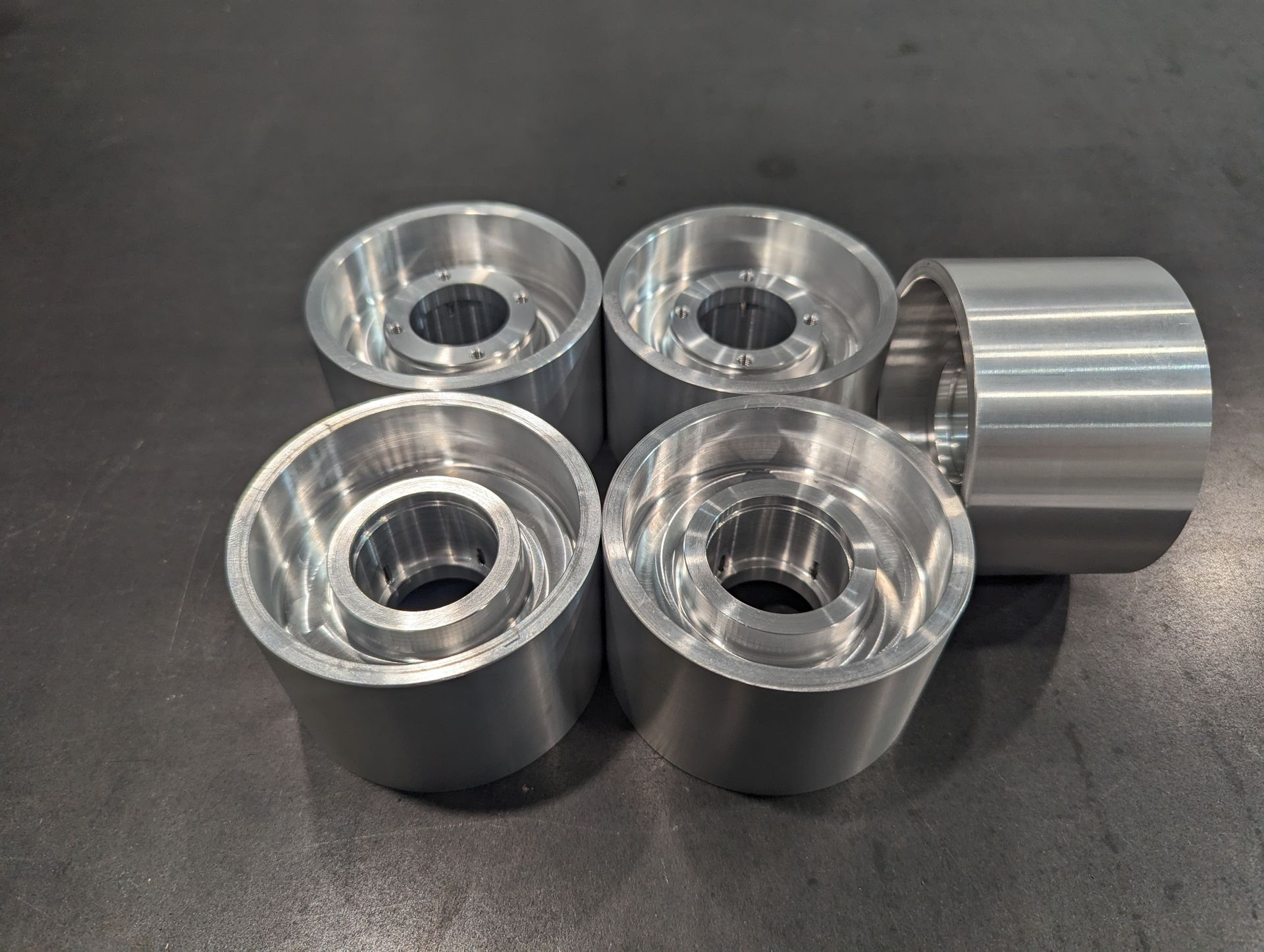Four aluminum wheels with holes in them are sitting on a table.