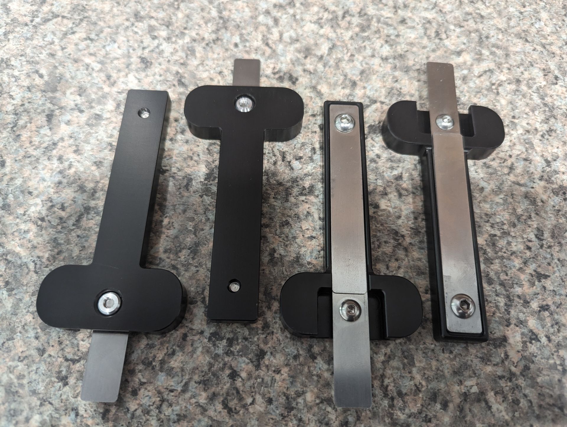 Three pieces of metal are sitting on a granite surface.