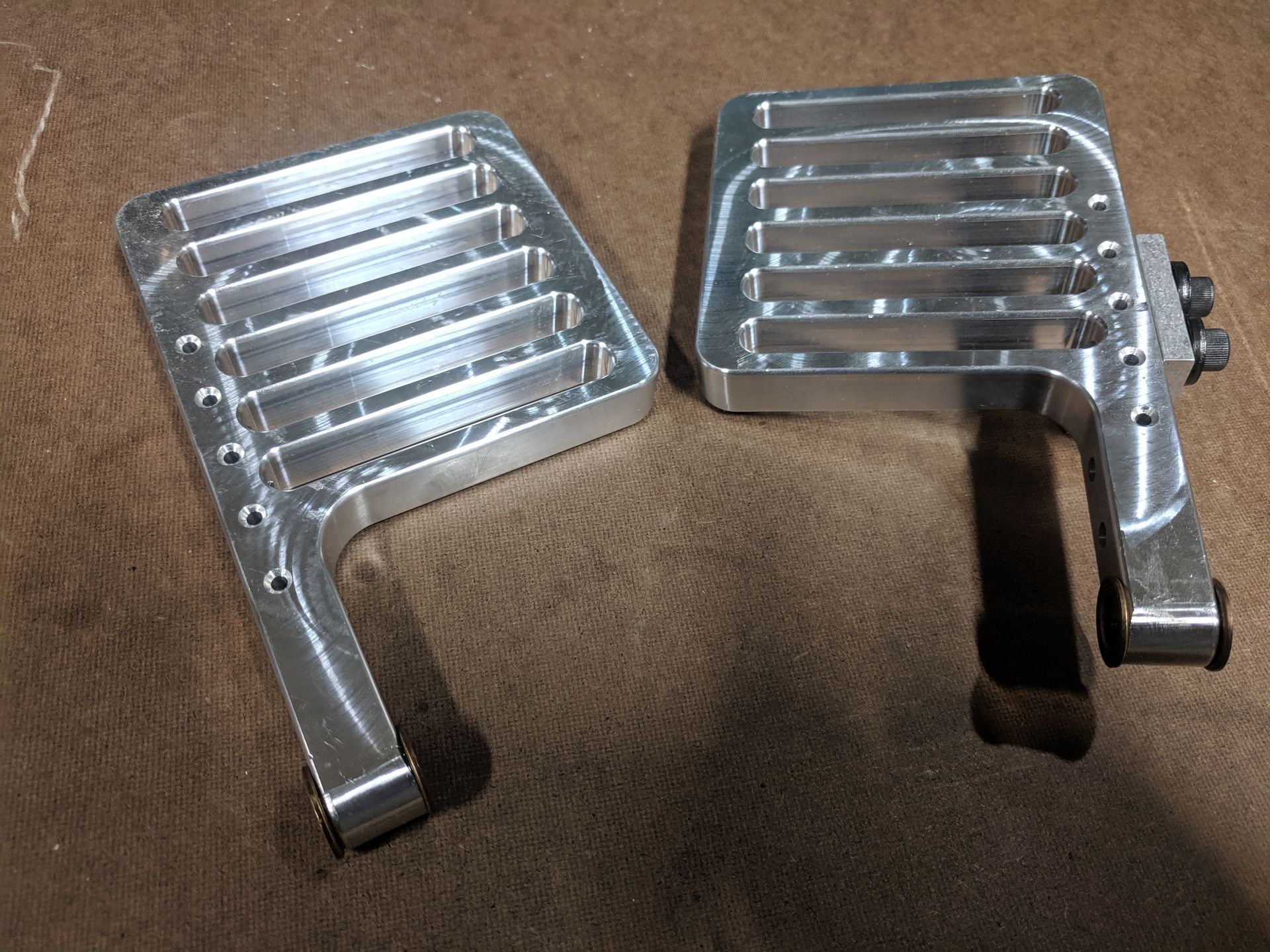 Two pieces of metal are sitting on a brown surface.