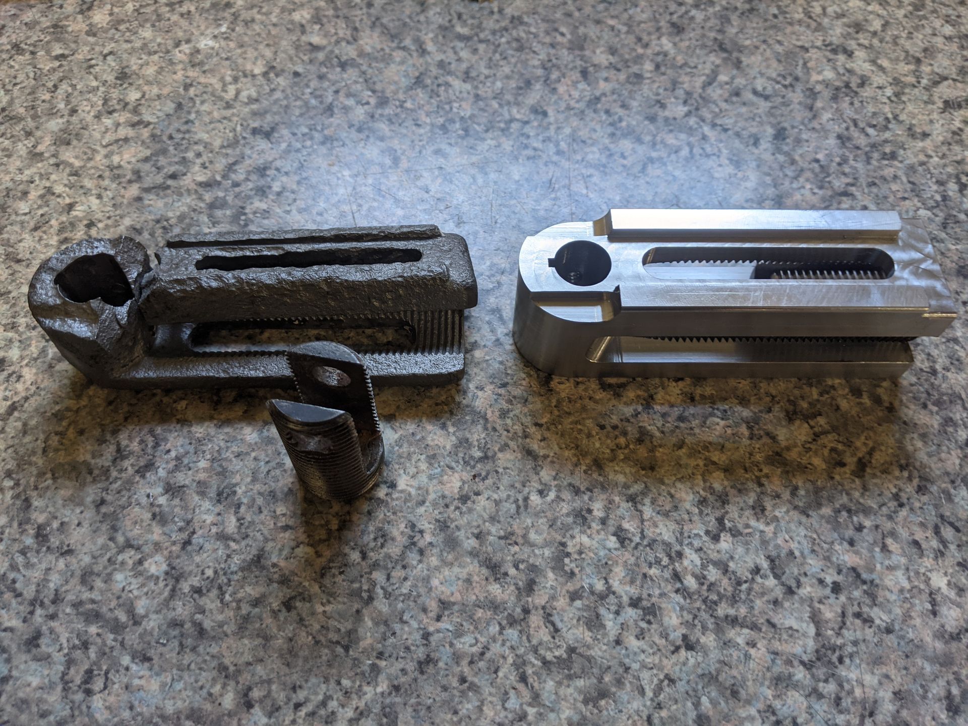 Two pieces of metal are sitting on a marble surface.