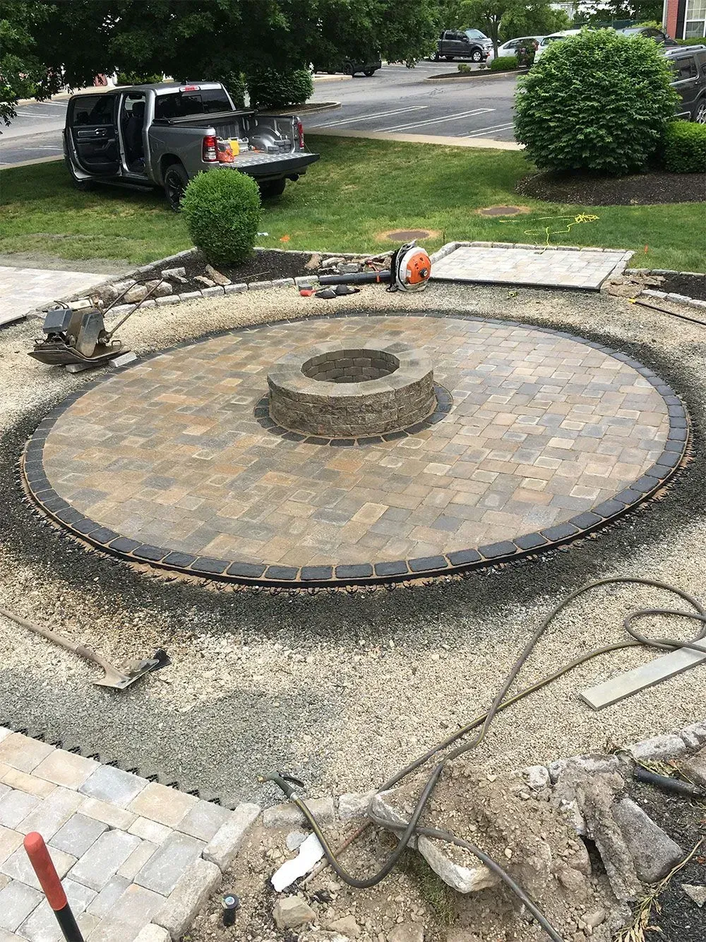 Circular brick patio under construction with central fire pit.