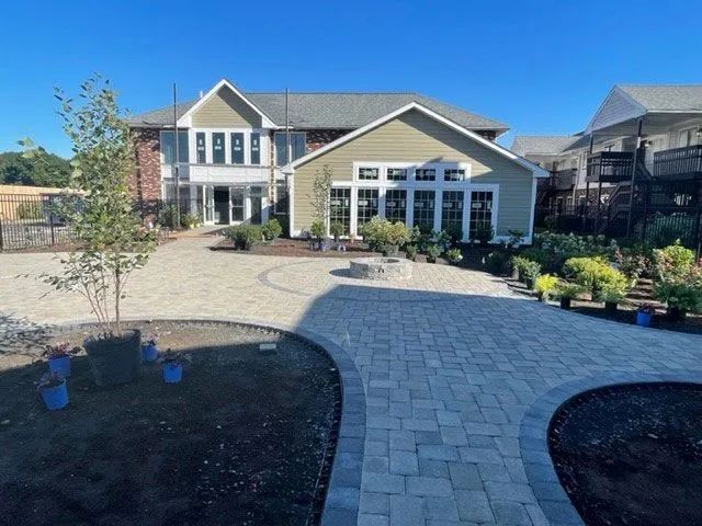 Backyard patio with paved pathways, fire pit, and a multi-story house.