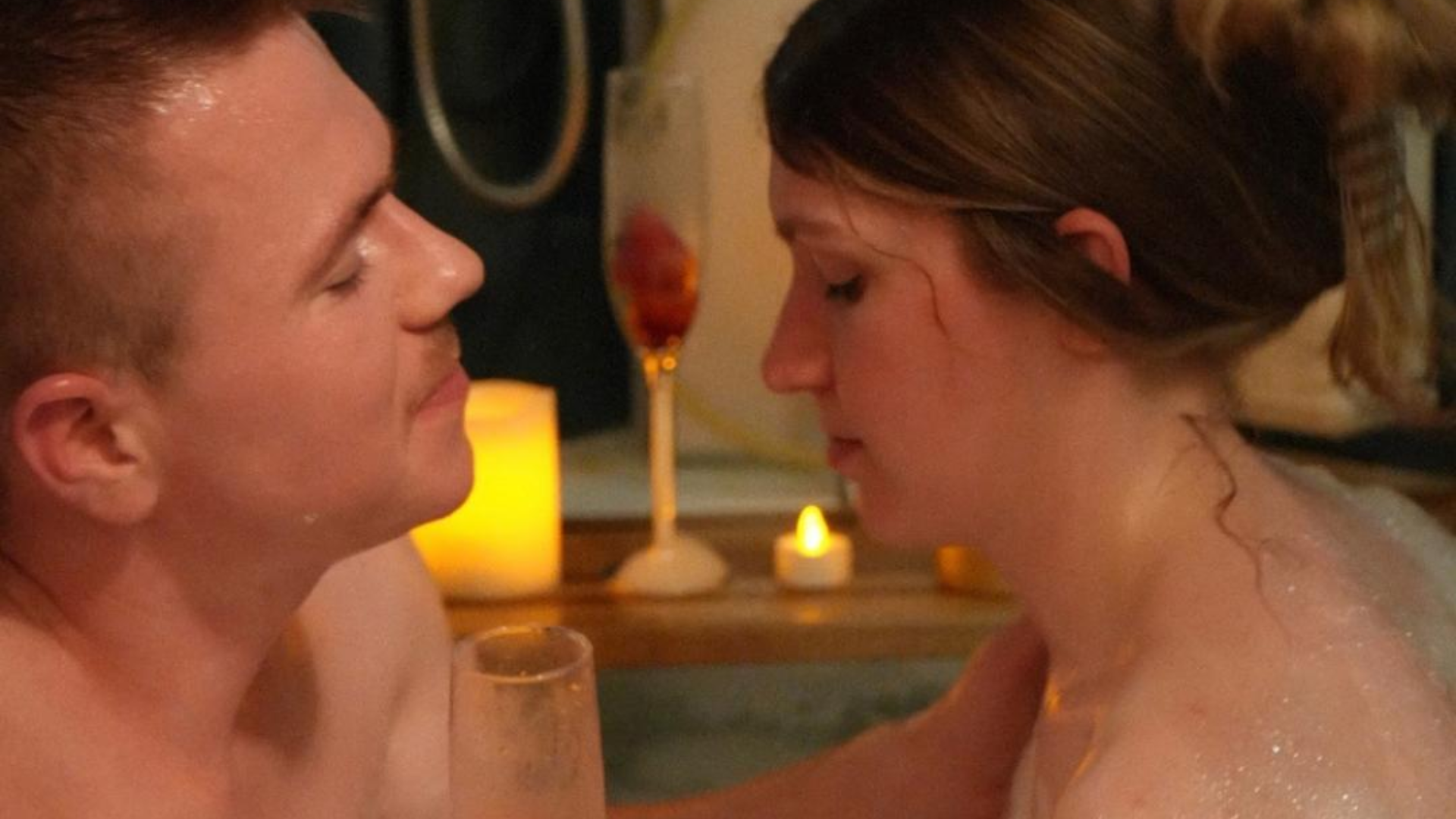 a man and a woman are kissing in a bathtub