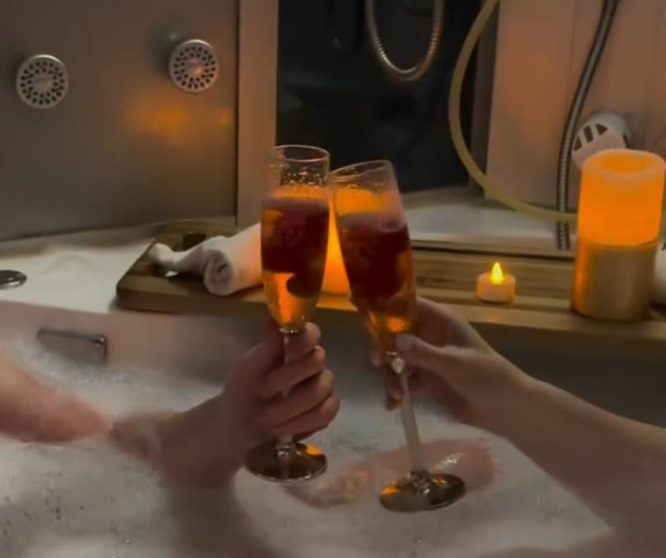 two people are toasting with champagne in a bathtub .
