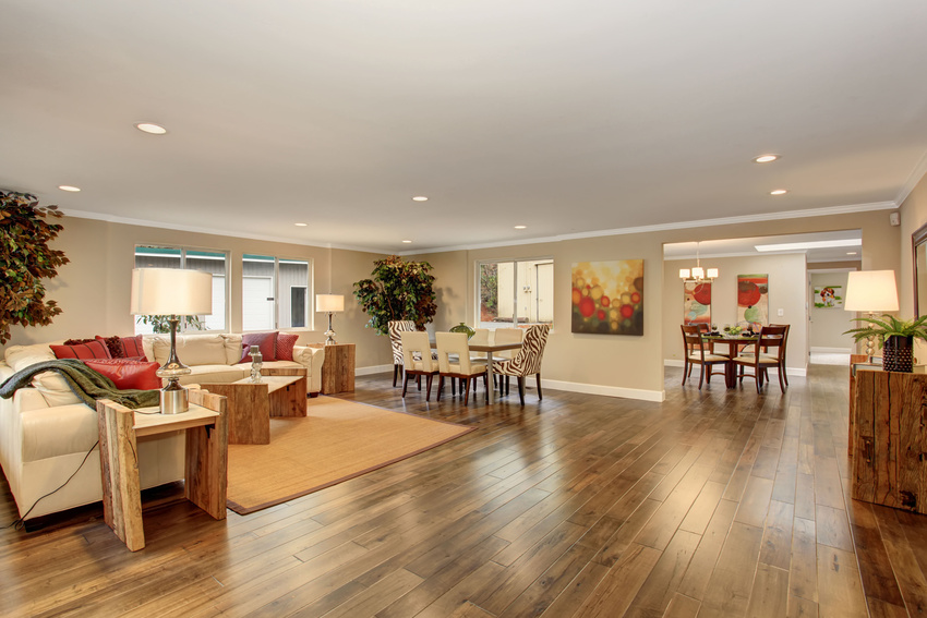 A living room with hardwood floors and a dining room in the background.