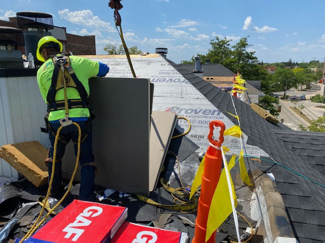 Roofer in safety gear installing HVAC unit on a rooftop, sunny day.
