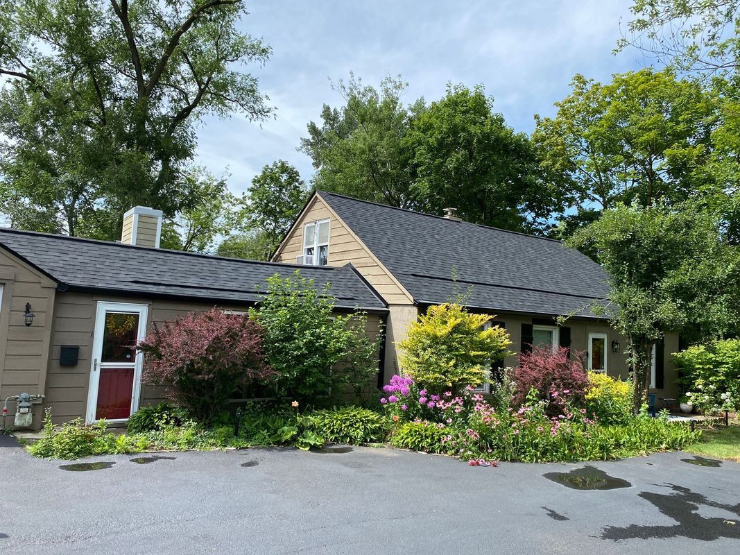 Brown house with a dark roof and a garden in front. Overcast sky.