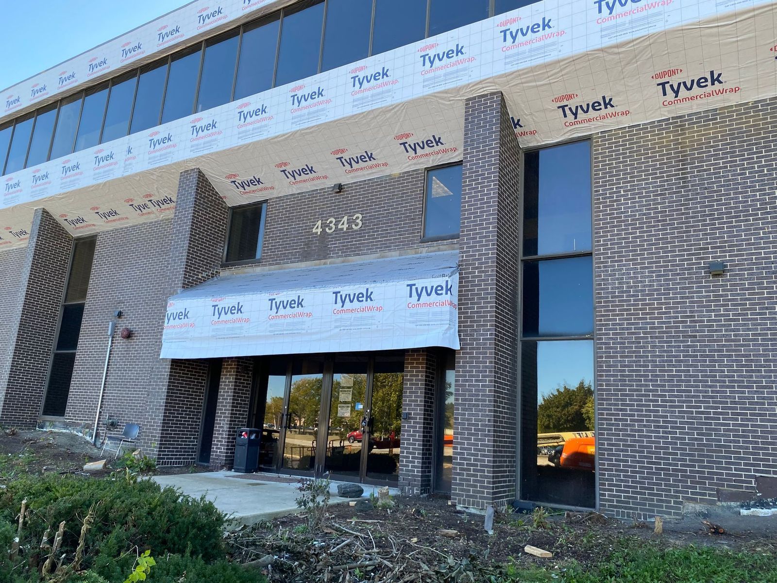 Exterior of a building under construction, address 4343, with Tyvek covering and dark brick.