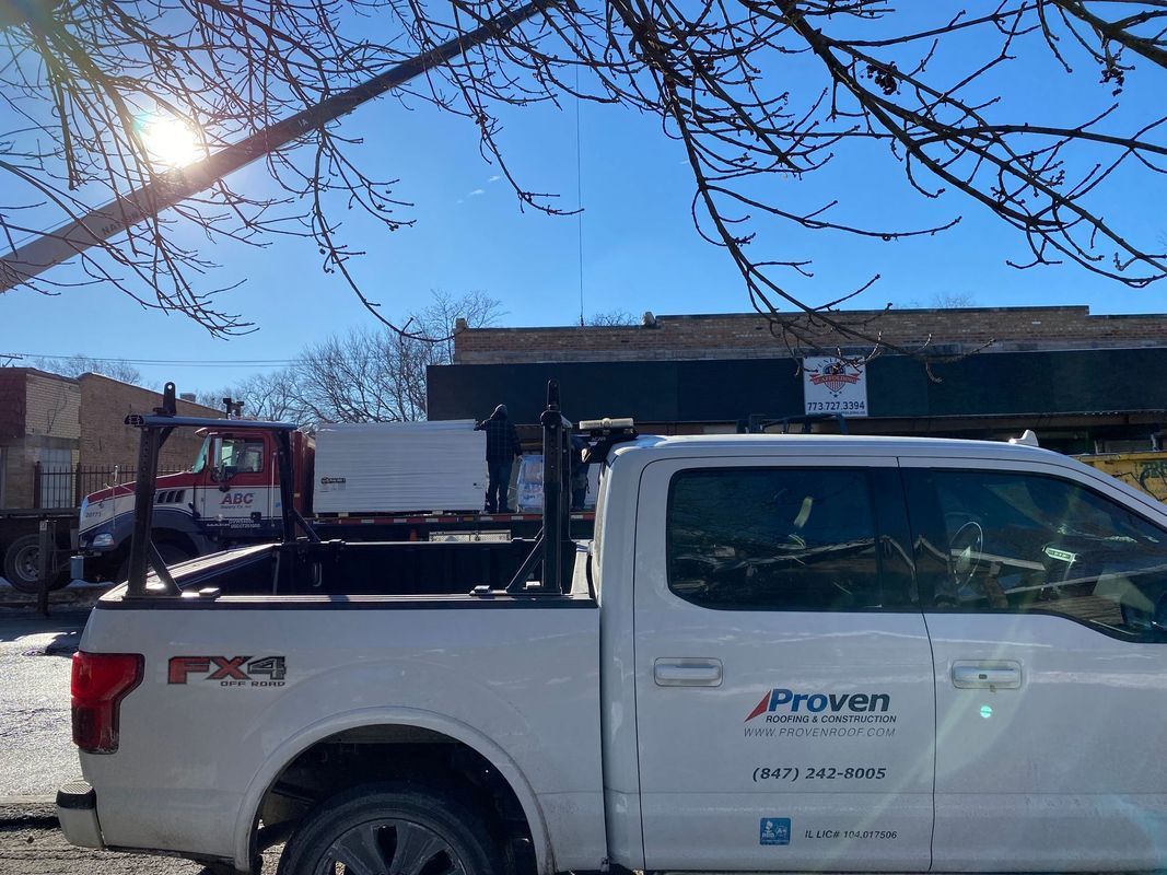 White work truck parked on a street with equipment. Building in the background, sunny day.