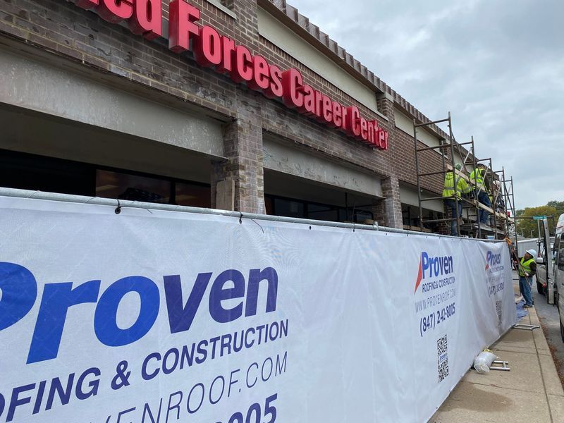 Exterior of a Armed Forces Career Center building under construction; white banner with company name in front.
