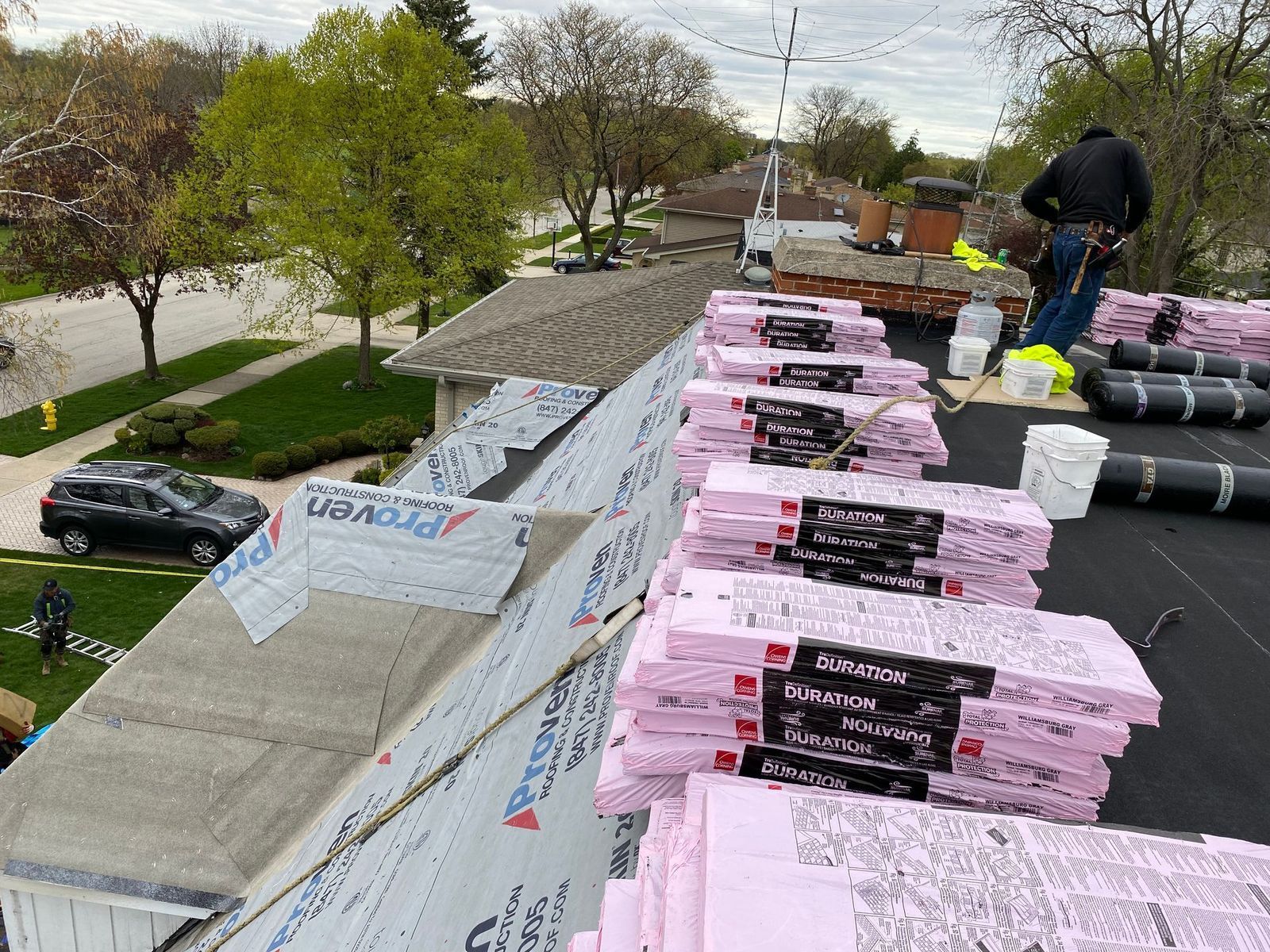 Workers installing pink insulation on a roof. Bundles of insulation and tools are visible.