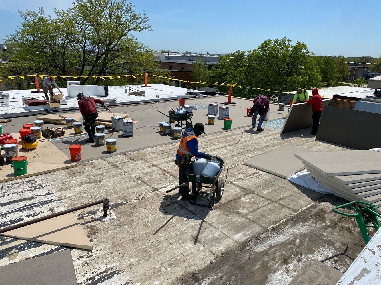 Construction workers on a rooftop, mixing materials and laying down new sections of surface.