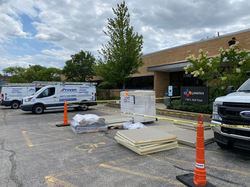 Exterior of a building with construction materials, work vans, and caution tape.