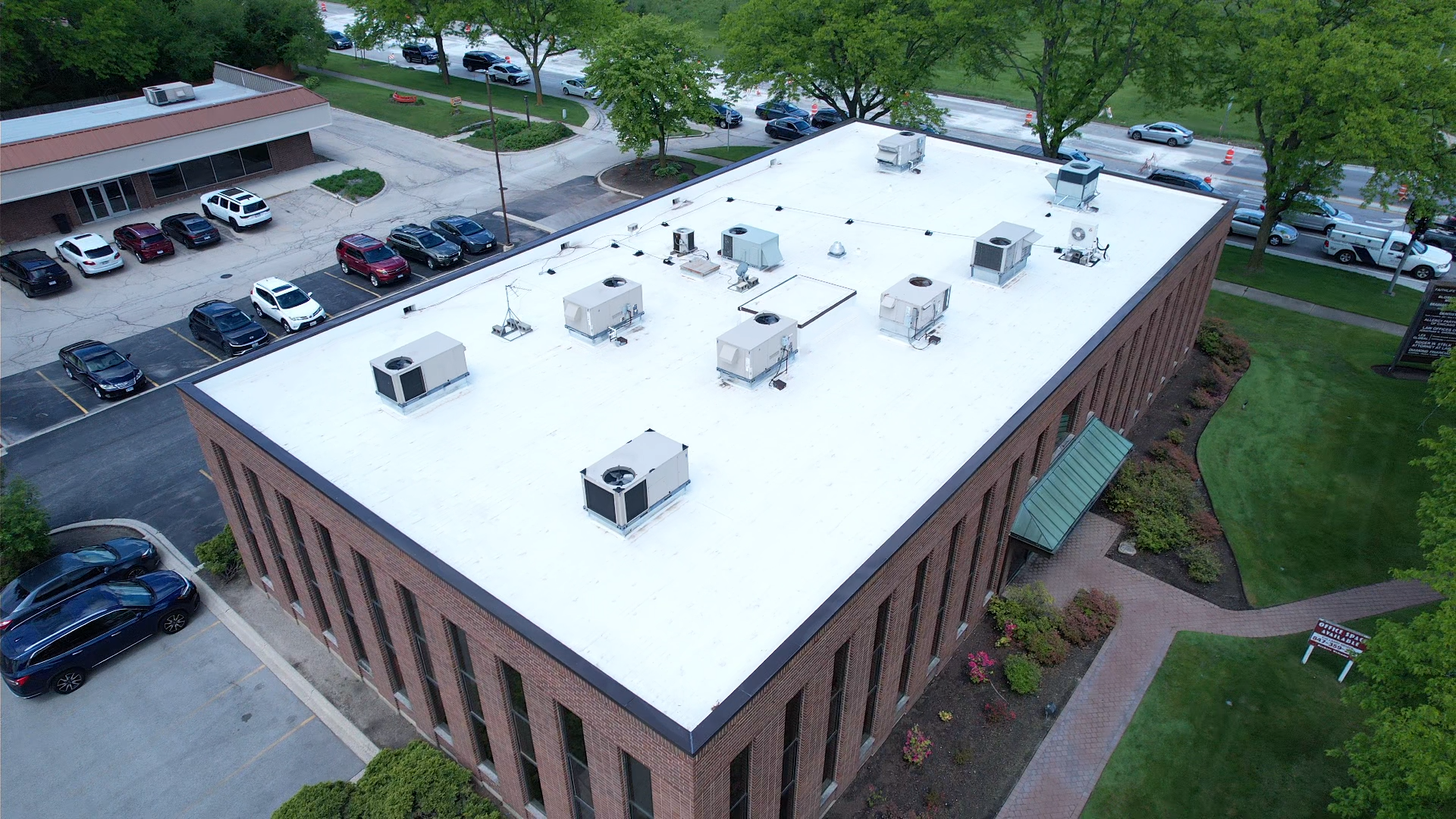 Aerial view of a commercial building with a white flat roof and several HVAC units.