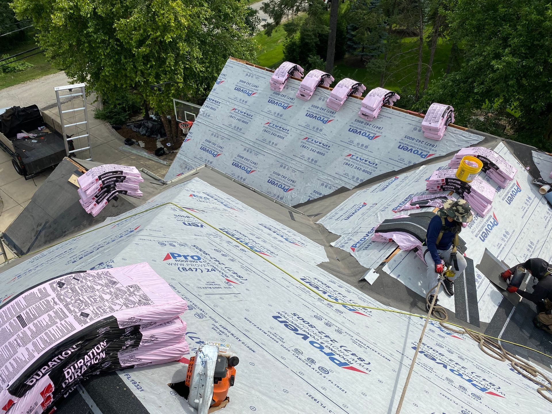 Roofers working on a house roof, installing pink insulation.