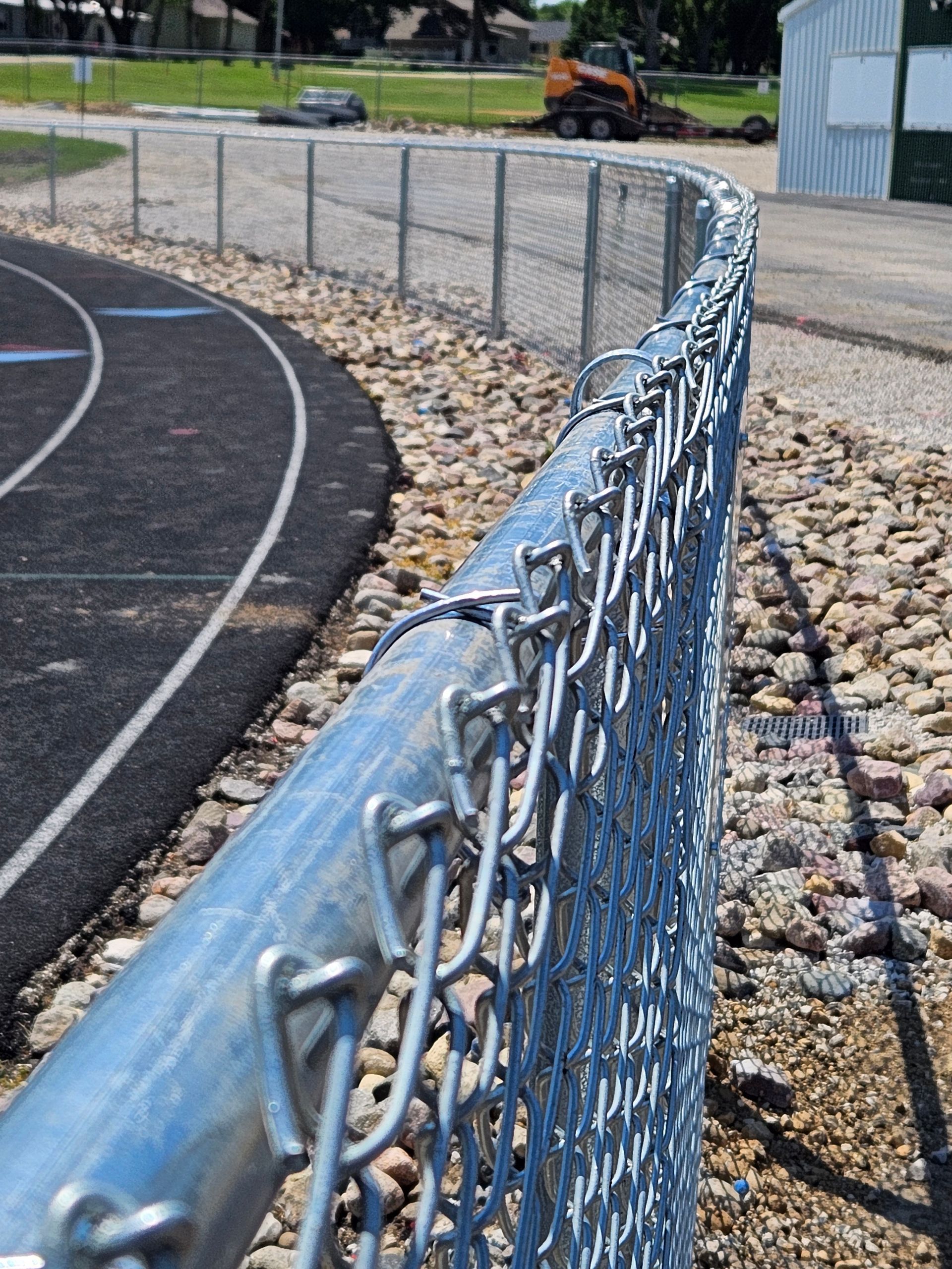 A chain link fence with a track in the background