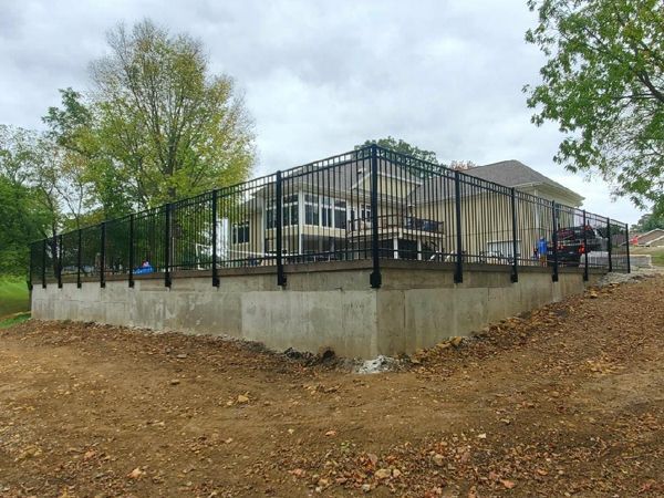 A large house with a fence around it and a concrete foundation.