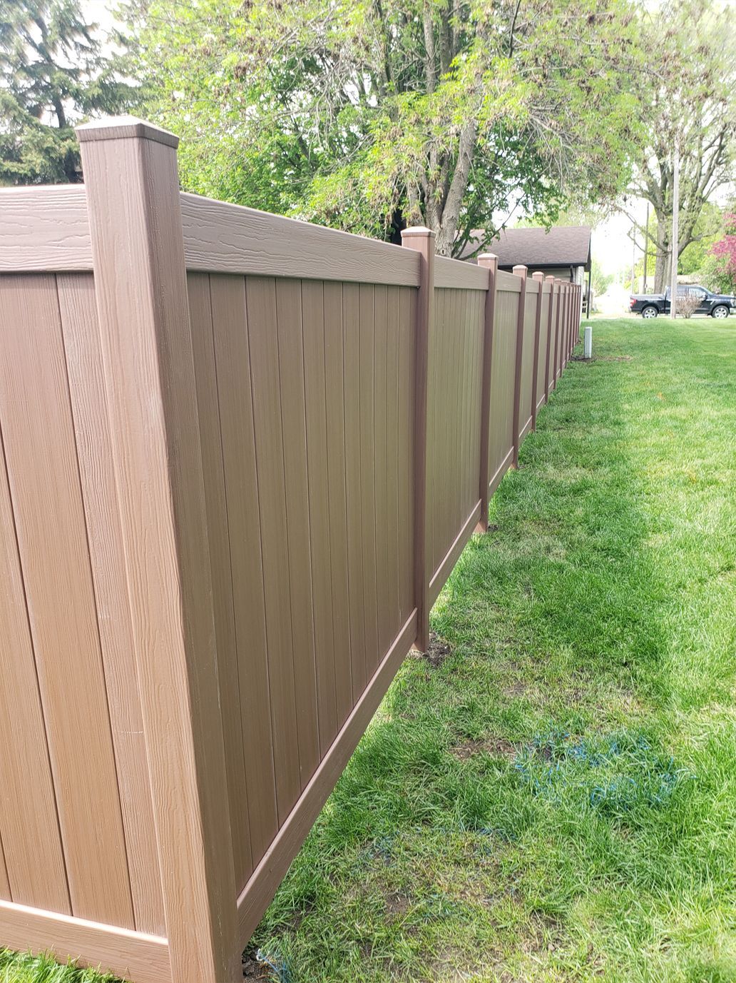 A brown fence is sitting in the middle of a lush green field.