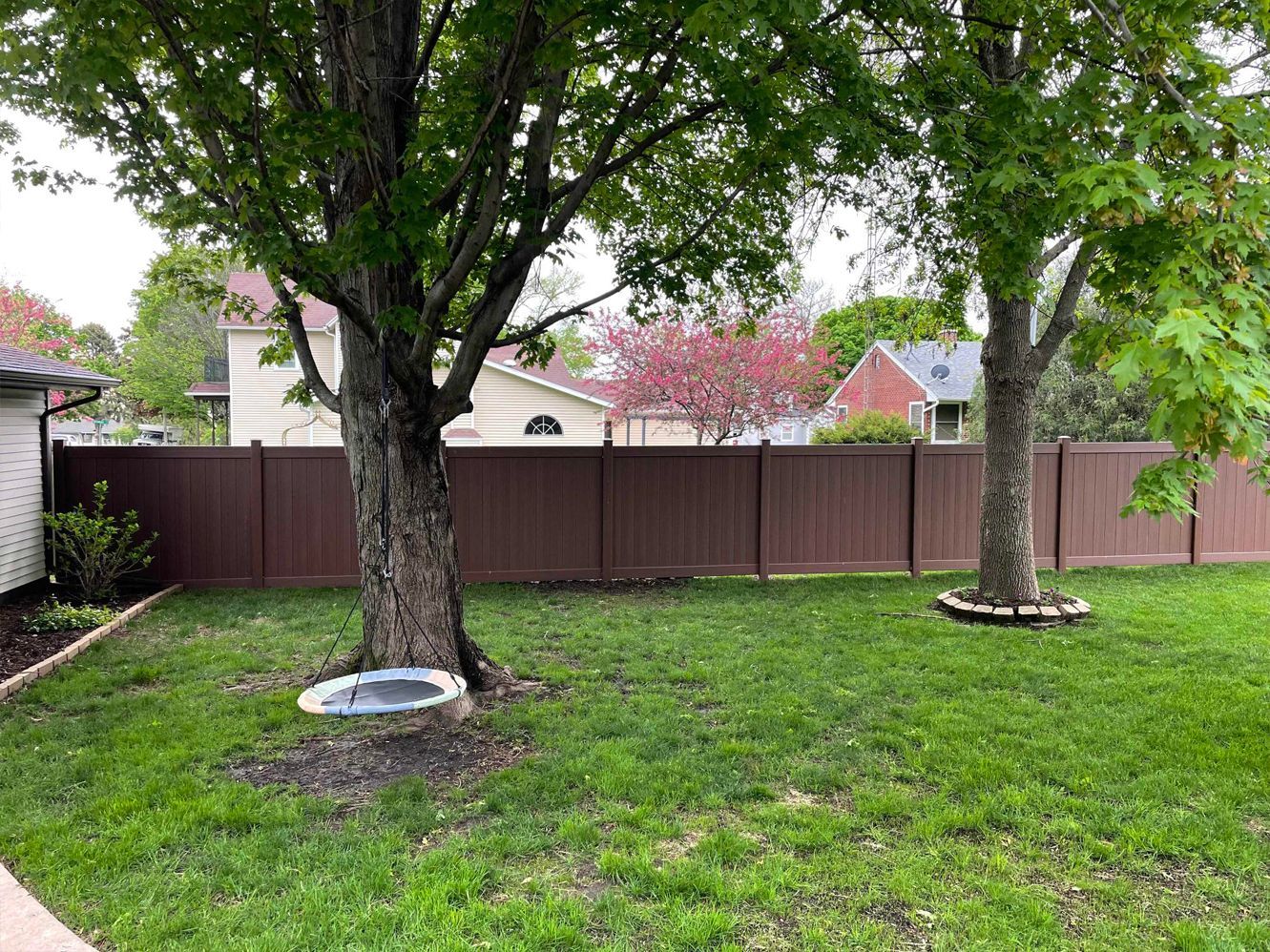 A backyard with a wooden fence and trees.