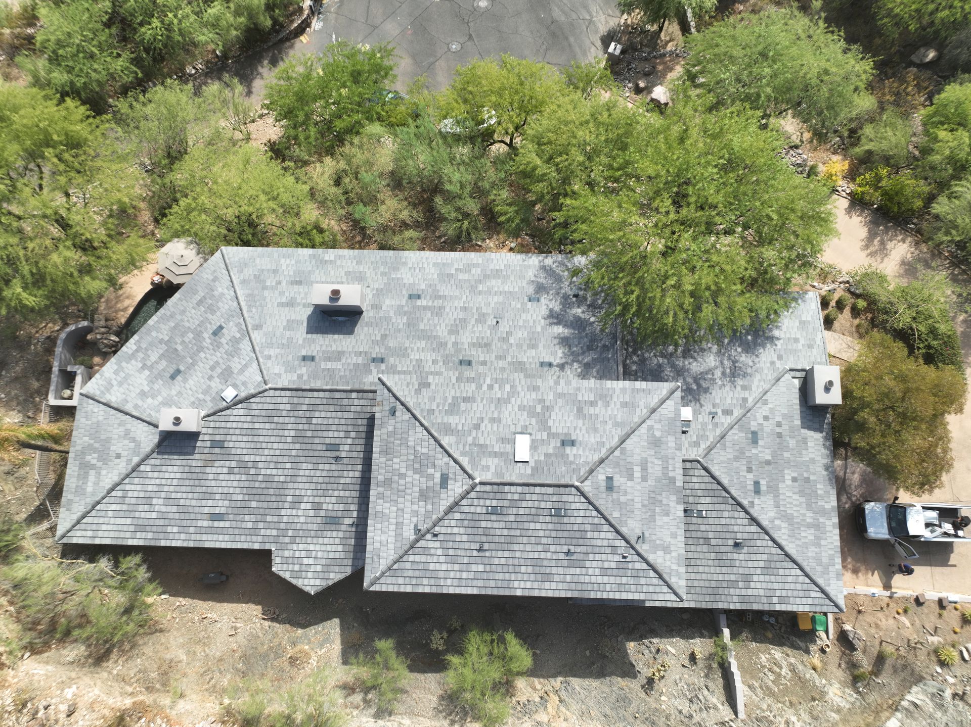 An aerial view of a house with a roof that is surrounded by trees.