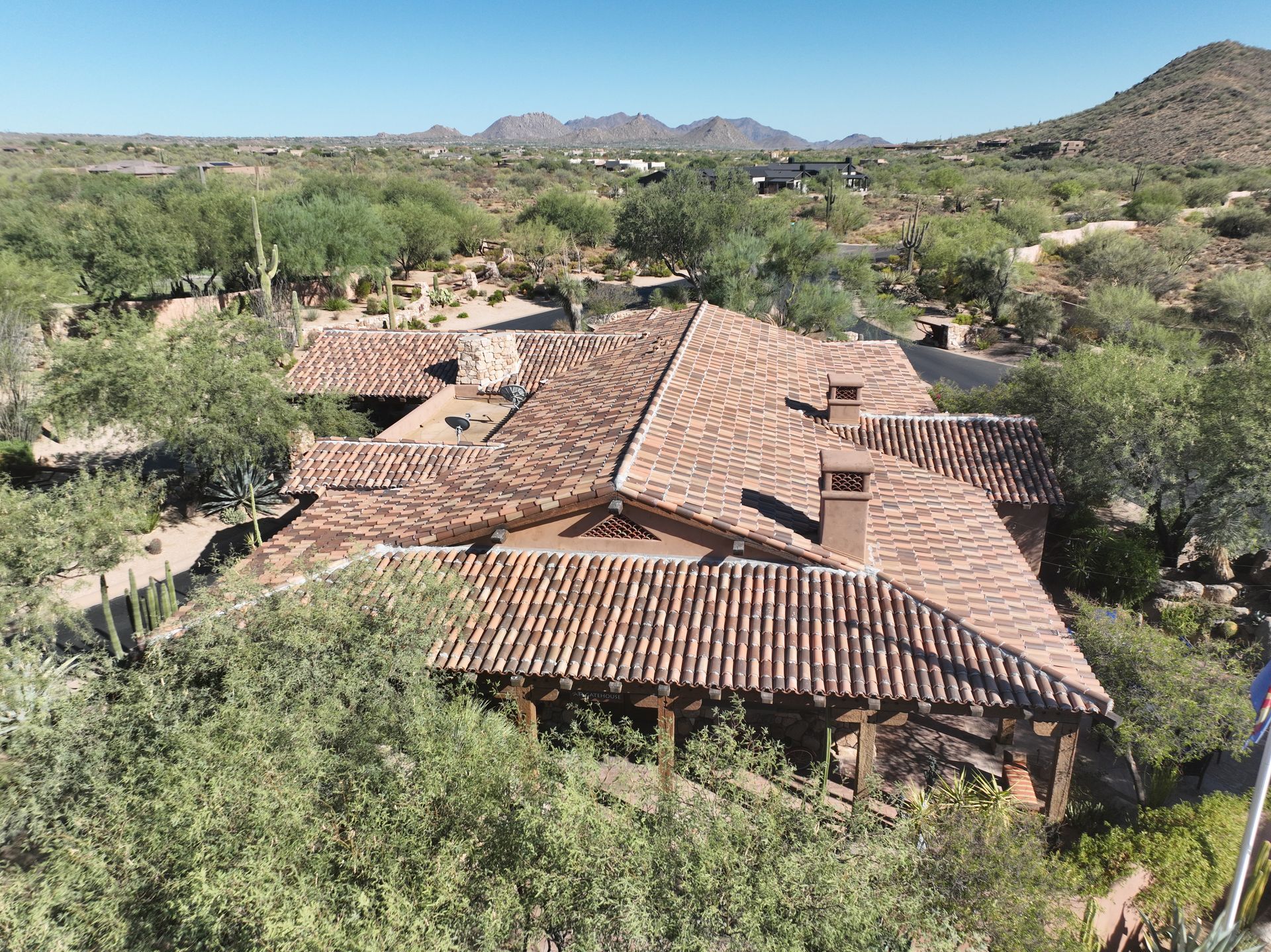 An aerial view of a large house in the desert with mountains in the background.